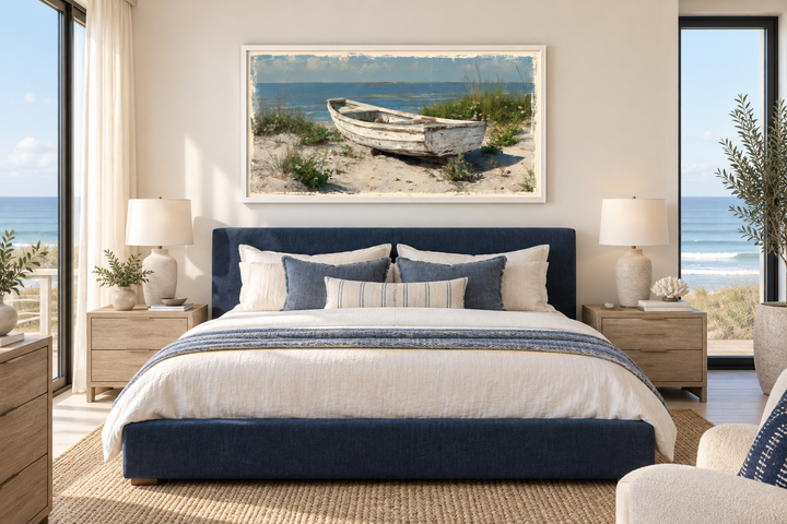 Old white boat on the beach coastal framed canvas wall art hanging above a blue bed in a bedroom.