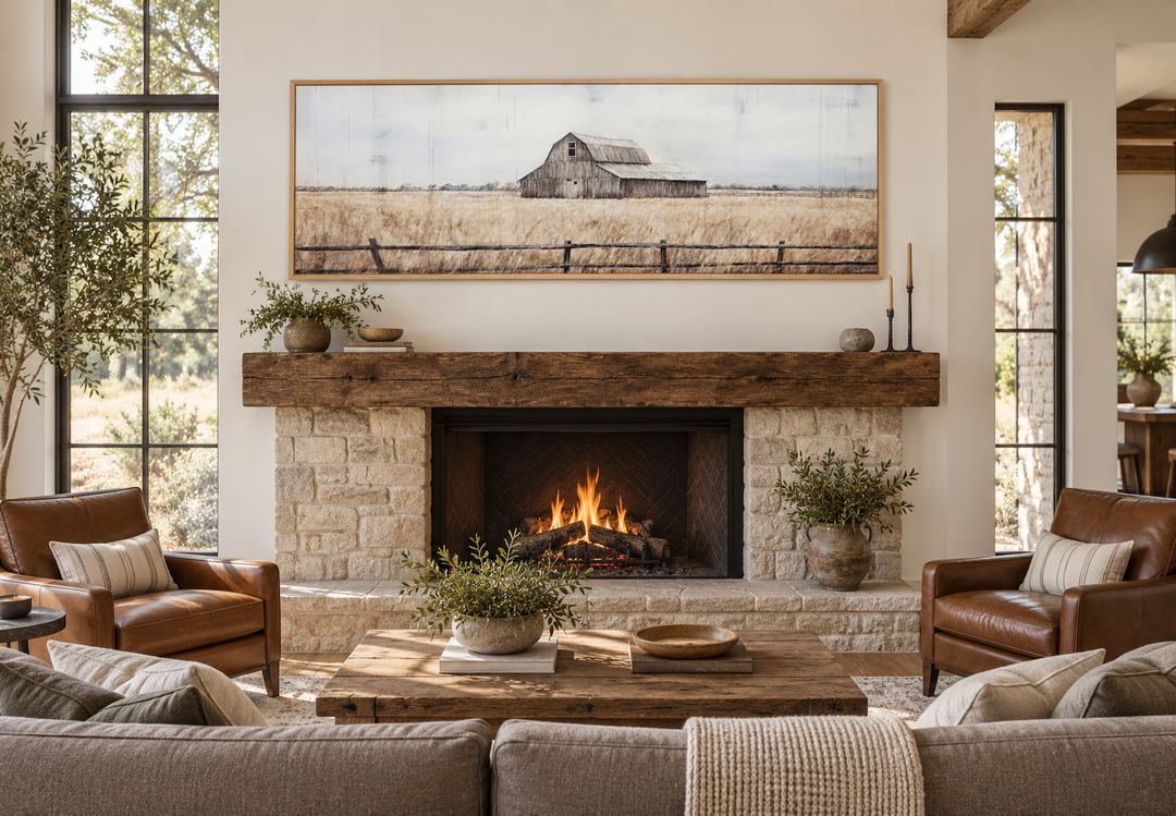 Rustic long narrow framed canvas painting of an old barn in a field above a fireplace mantel.