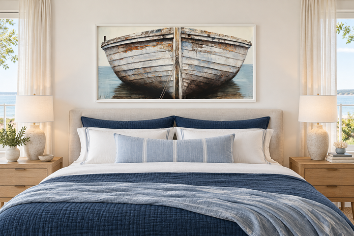 Rustic old white and brown boat close-up framed canvas wall art above a bed in a coastal bedroom.