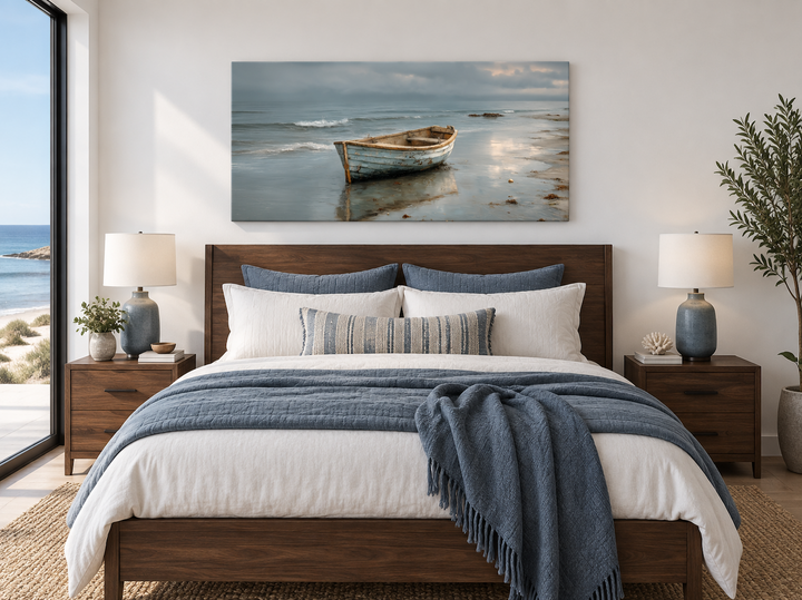 Rustic rowboat on beach coastal framed canvas wall art hanging above a bed in a beach house bedroom.