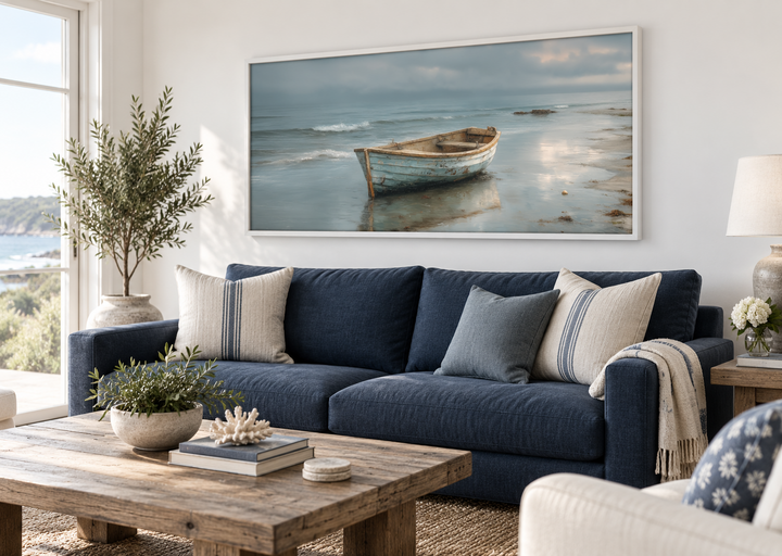 Rustic rowboat on beach coastal framed canvas wall art hanging above a navy blue sofa.