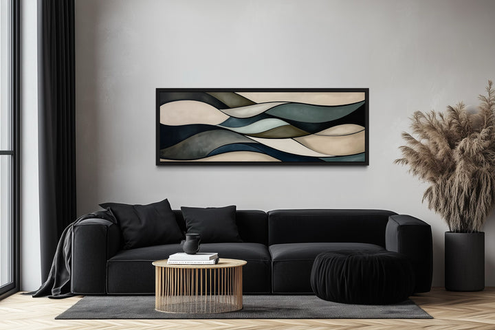 Sage green and brown modern abstract horizontal framed wall art hanging above a black sofa.