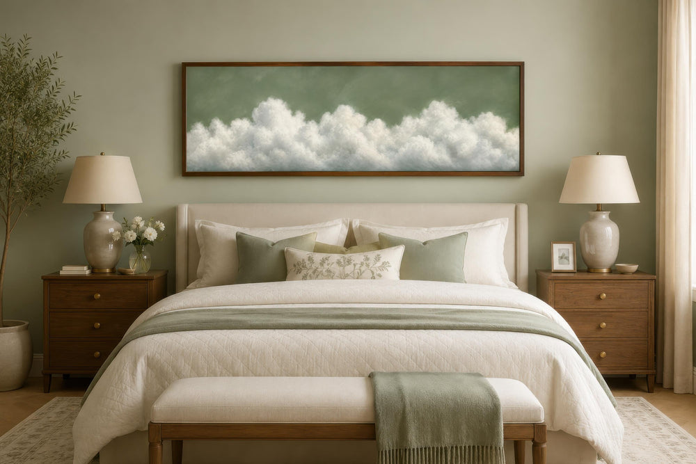 Long narrow sage green canvas art with white clouds hanging above a bed in a neutral bedroom.