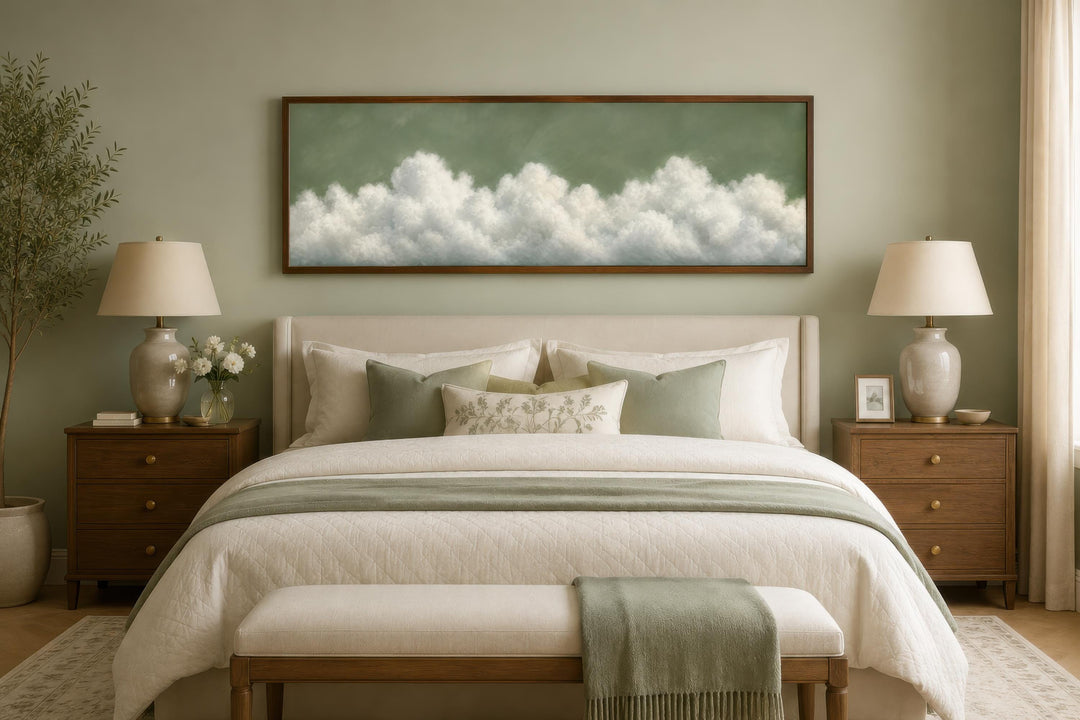 Long narrow sage green canvas art with white clouds hanging above a bed in a neutral bedroom.