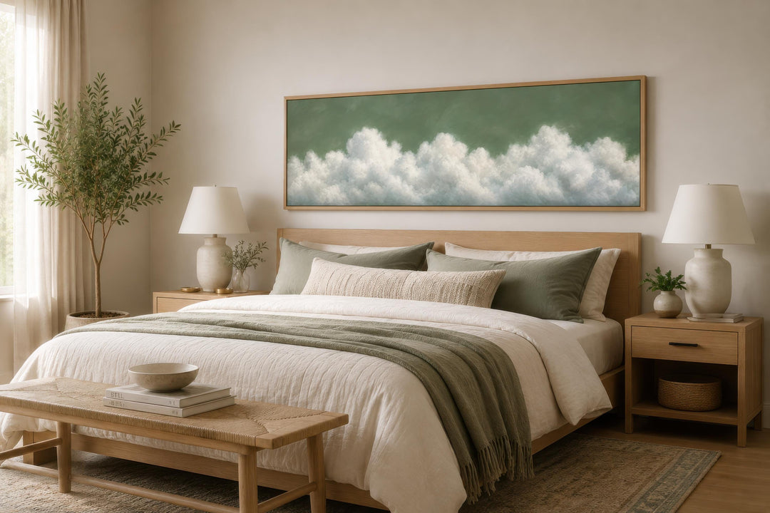 Sage green long narrow canvas wall art with soft white clouds hanging above a bed.