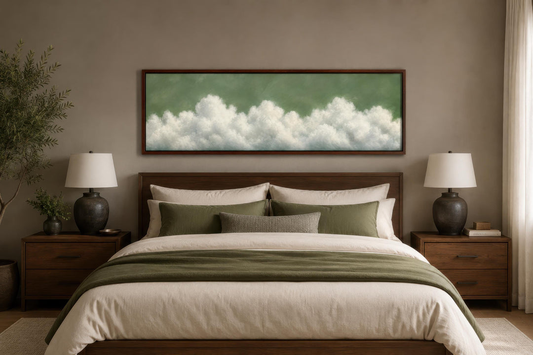 Sage green long narrow canvas wall art with billowing white clouds hanging above a bed.