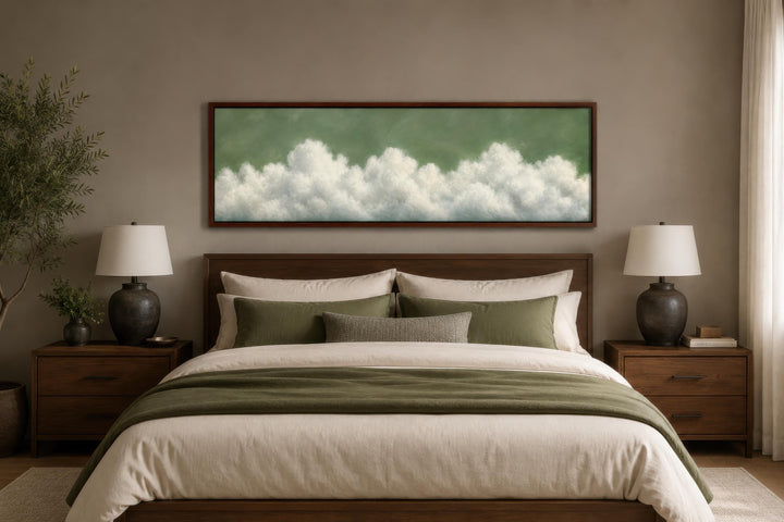 Sage green long narrow canvas wall art with billowing white clouds hanging above a bed.