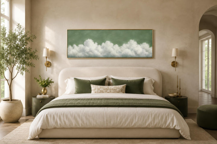 Sage green horizontal canvas art with soft white clouds hanging above a bed in a neutral bedroom.
