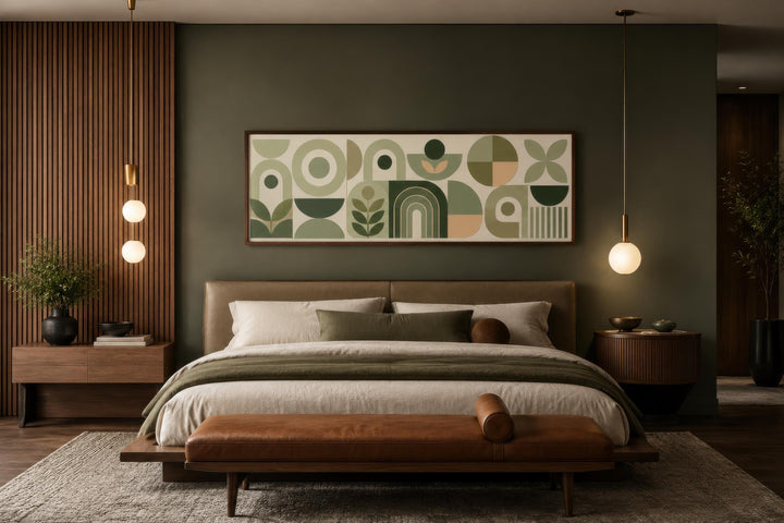 Sage green long narrow geometric canvas print with Bauhaus-style shapes above a bed in a bedroom.