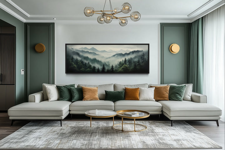 Sage green foggy pine forest and mountain landscape wall art above a sofa in a modern living room.