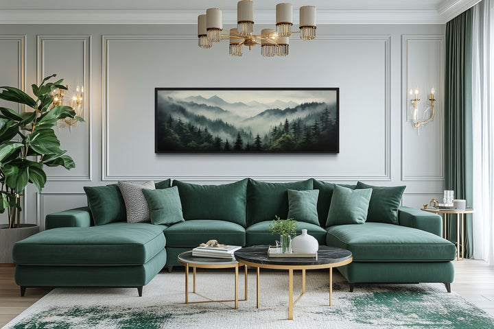 Sage green moody foggy pine forest and mountains landscape wall art above a green sectional sofa.