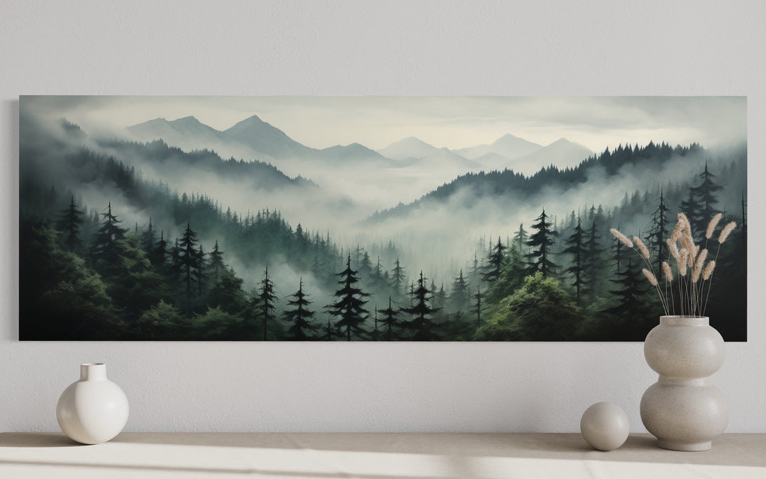 Sage green moody foggy pine forest and mountain landscape panoramic wall art above a console table.