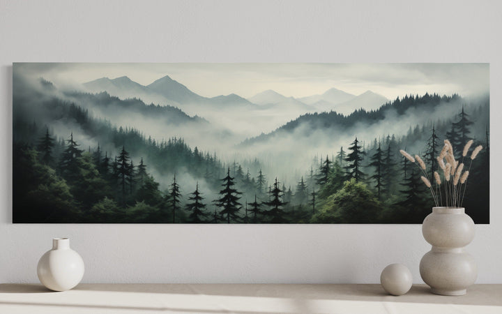 Sage green moody foggy pine forest and mountain landscape panoramic wall art above a console table.