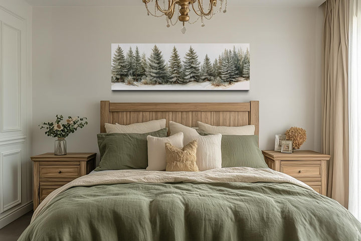 Panoramic canvas wall art featuring sage green pine trees hanging above a bed in a neutral bedroom.