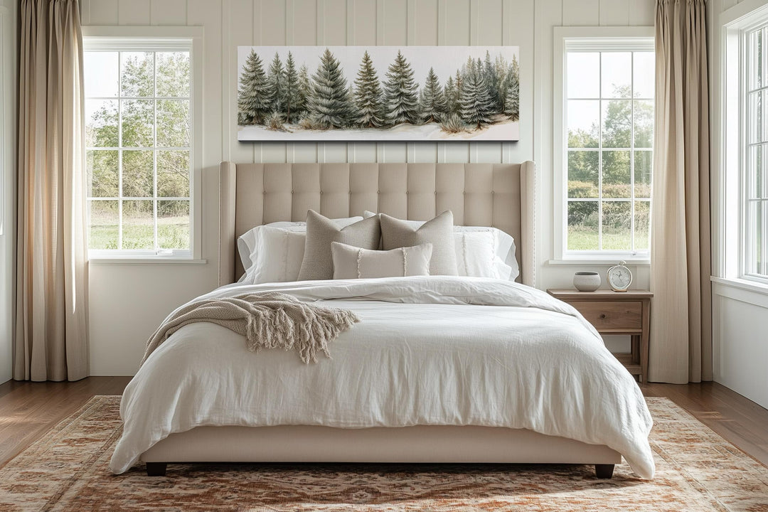 A long horizontal canvas of sage green pine trees hangs above a bed in a neutral-toned bedroom.