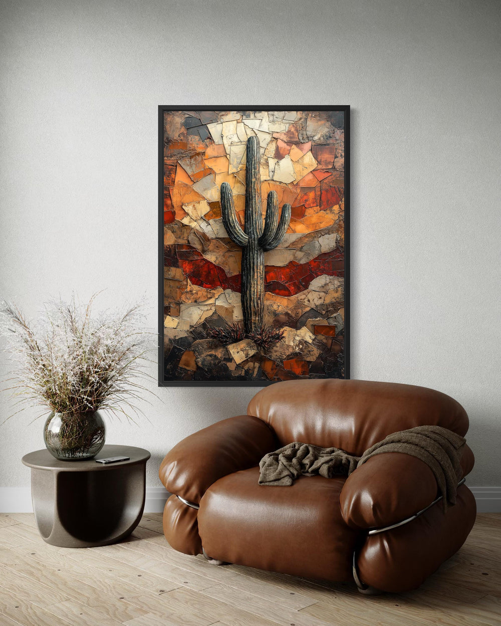 Saguaro cactus wall art in a rustic mosaic style hangs above a brown leather armchair.