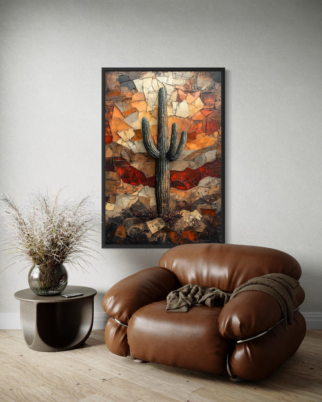 Saguaro cactus wall art in a rustic mosaic style hangs above a brown leather armchair.
