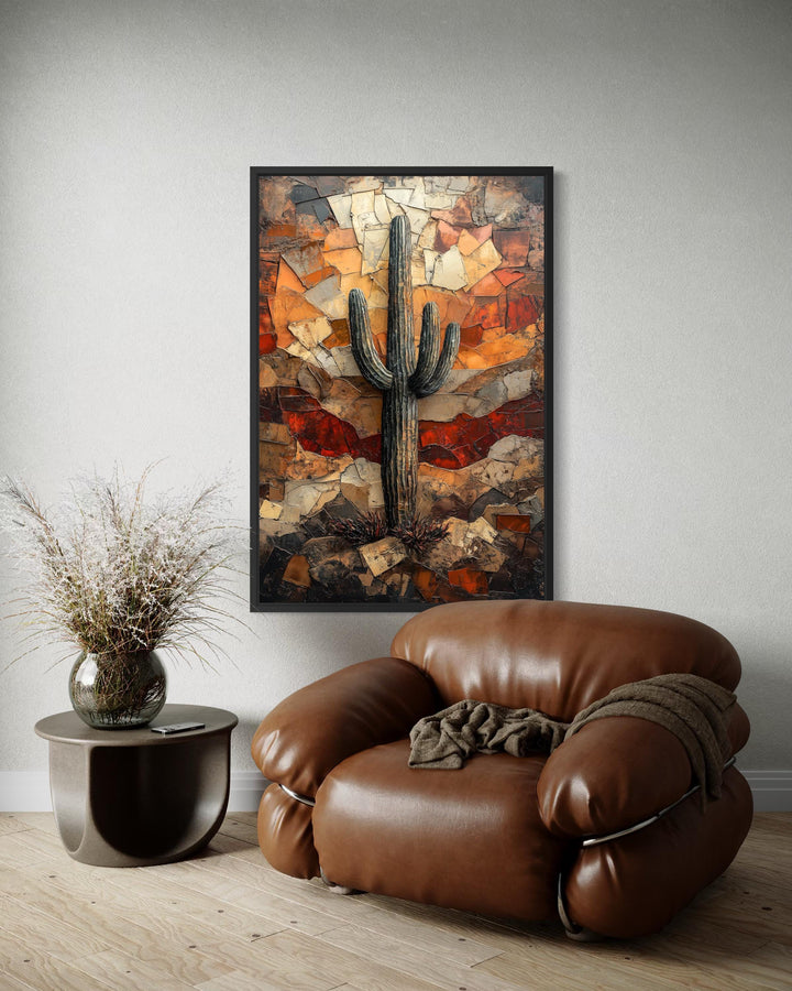 Saguaro cactus wall art in a rustic mosaic style hangs above a brown leather armchair.