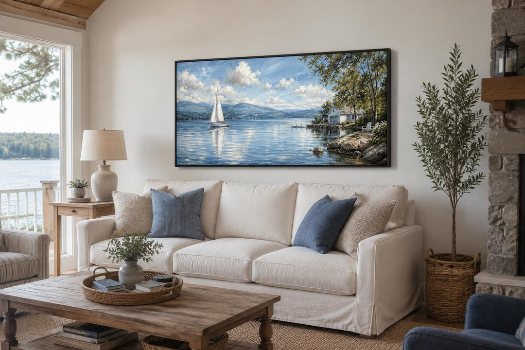 Sailboat in mountain lake canvas print hanging above a white sofa in a cozy living room.