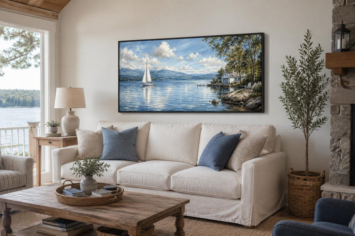 Sailboat in mountain lake canvas print hanging above a white sofa in a cozy living room.