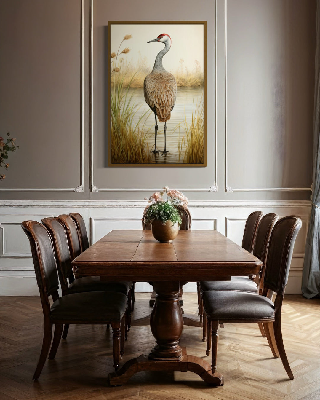 Framed canvas wall art of a sandhill crane in a marsh, hanging above a wooden dining table.