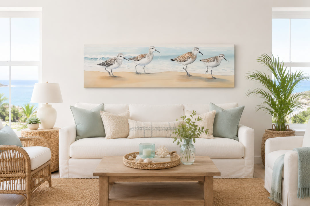 Panoramic framed canvas wall art of four sandpipers walking along a sandy beach shoreline.