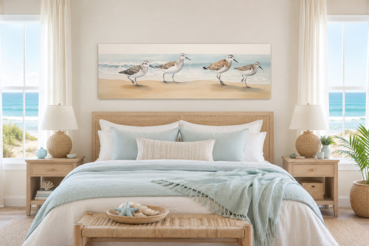 Sandpipers Walking On The Beach horizontal framed canvas wall art above a bed in a coastal bedroom.