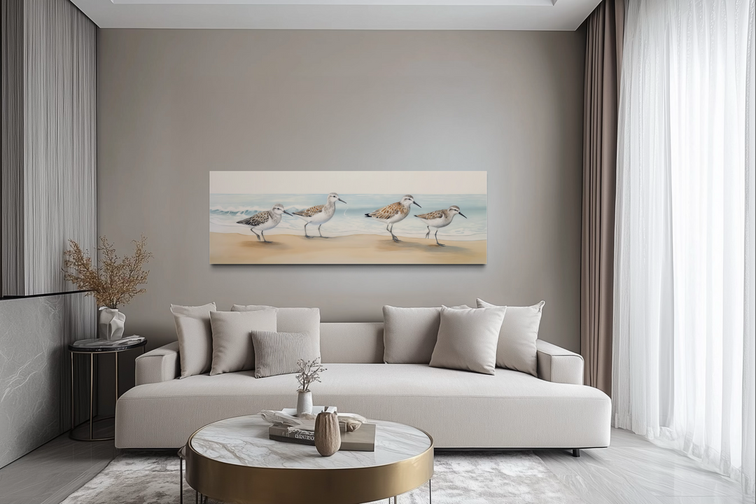 Sandpipers walking on the beach horizontal framed canvas wall art above a modern beige sofa.