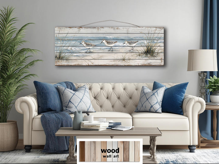 Sandpipers on the beach long narrow wood wall art displayed above a sofa in a coastal living room.