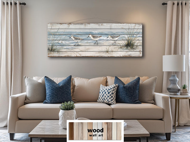 Long narrow wood wall art featuring sandpipers on a beach, hung above a neutral sofa.
