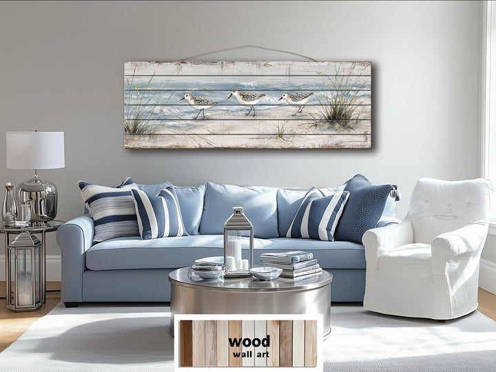 Long narrow wood wall art featuring sandpipers on a beach, hanging above a blue sofa.
