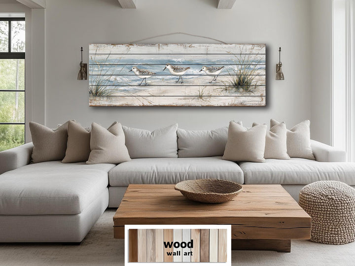 Long narrow wood wall art featuring three sandpipers on a beach, hanging above a sofa.