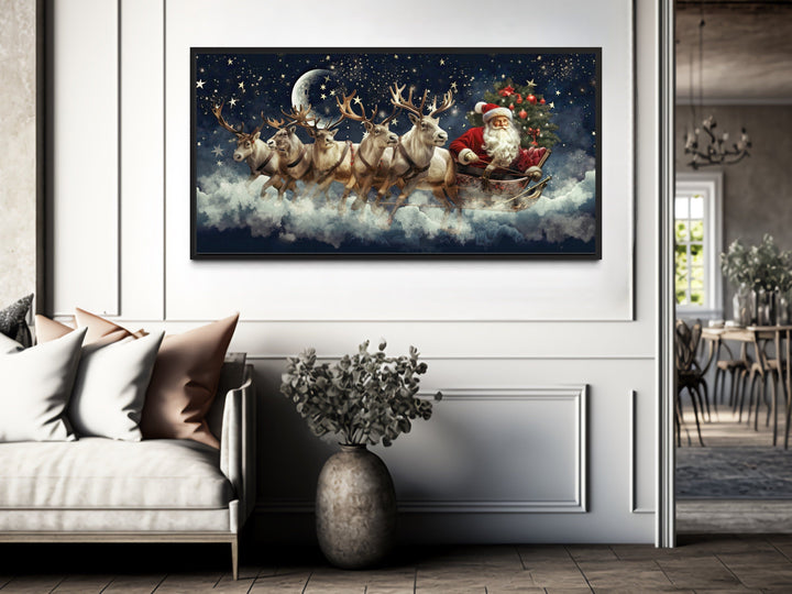 Santa Claus in a sleigh pulled by reindeer canvas wall art hanging in a modern living room.
