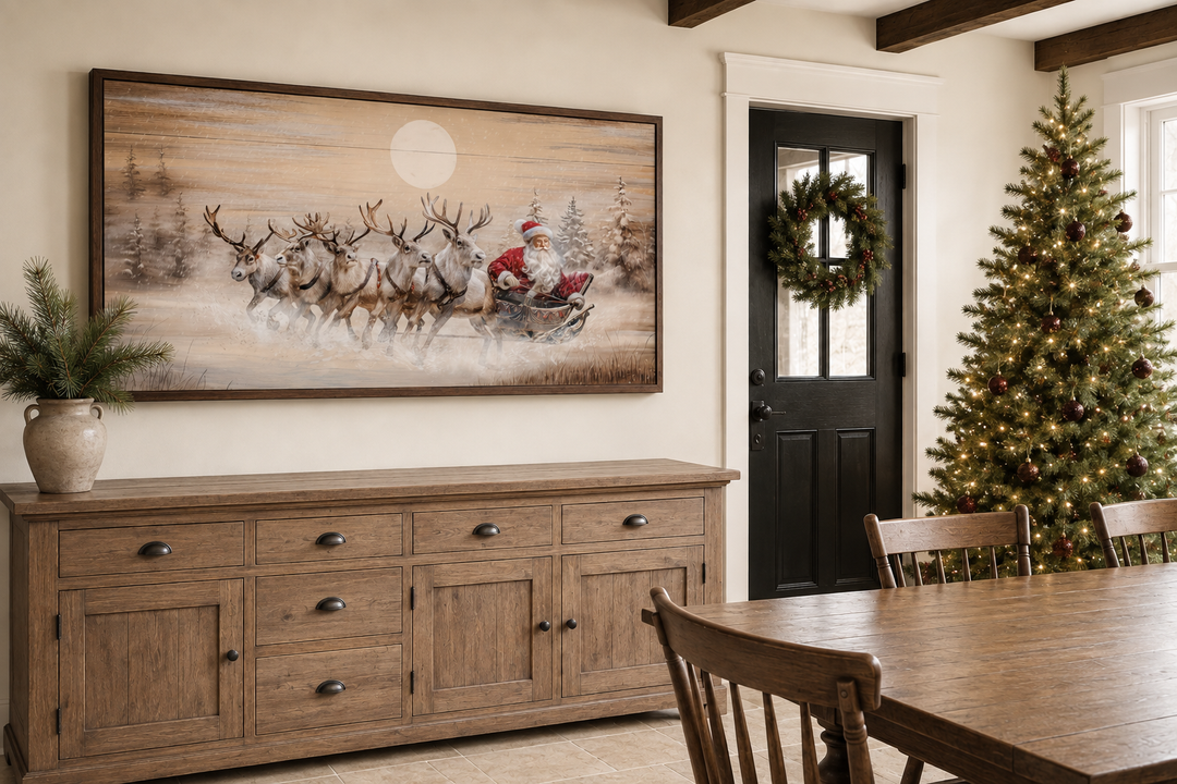 Rustic Santa Claus in sleigh with reindeer wall art above a wooden sideboard in a farmhouse room.