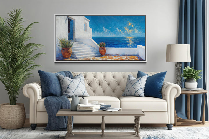 Santorini coastal villa wall art featuring a blue door and ocean view above a white sofa.