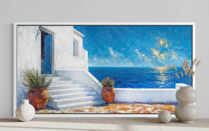 A framed impressionist painting of a Santorini villa overlooking the blue Mediterranean Sea.