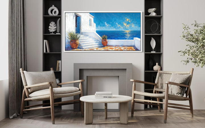 A horizontal canvas painting of a Santorini villa overlooking the blue Aegean Sea in a modern room.