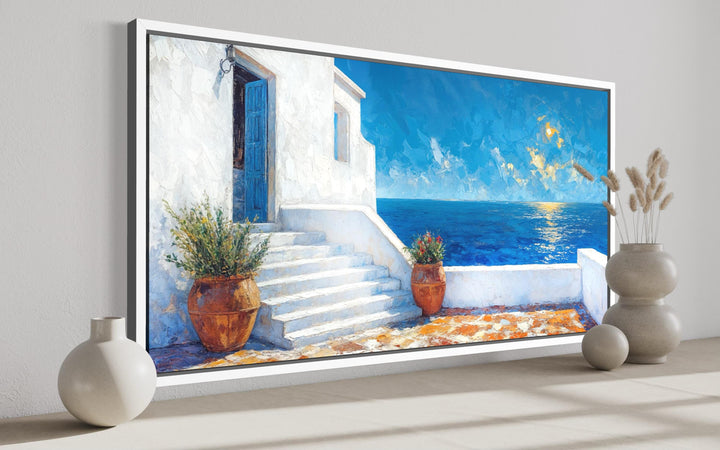 Santorini Greek island coastal wall art featuring a white villa and blue ocean view in a frame.