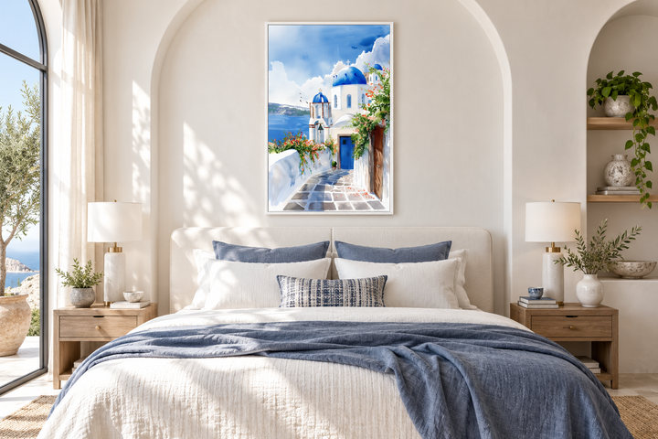 Santorini Greece watercolor wall art featuring blue-domed buildings above a bed in a neutral room.