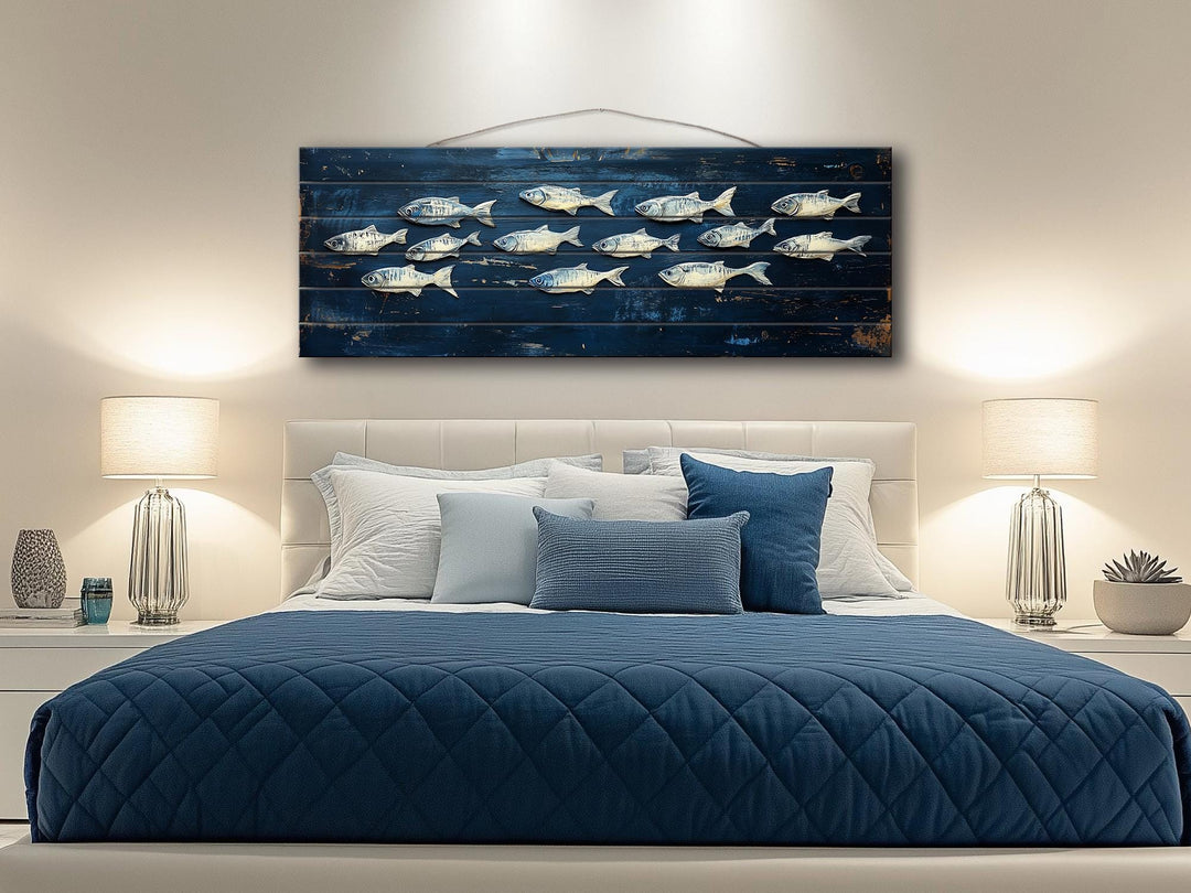 A long, narrow distressed wood wall art piece featuring a school of fish over a blue bed.