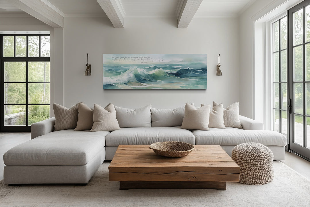 Horizontal framed canvas wall art of ocean waves with Psalm 93:4 scripture above a neutral sofa.