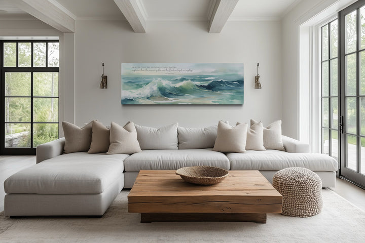 Horizontal framed canvas wall art of ocean waves with Psalm 93:4 scripture above a neutral sofa.