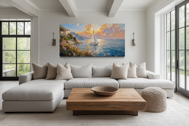 Seascape wall art of sailboats at sunset on a canvas print above a modern living room sofa.