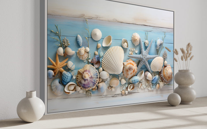 Seashells painting on blue wood coastal wall art displayed in a modern room with ceramic vases.