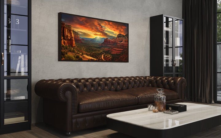 Framed Sedona sunset landscape canvas print hanging above a brown leather chesterfield sofa.
