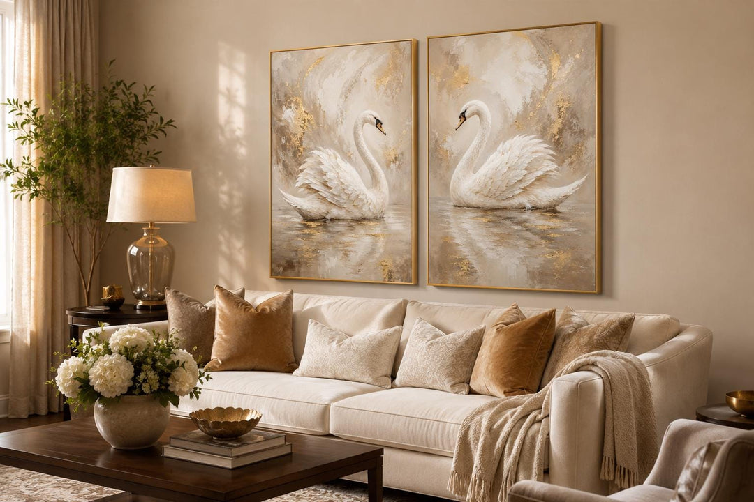 Set of 2 white swan canvas art prints with gold accents hanging above a cream sofa in a glam room.