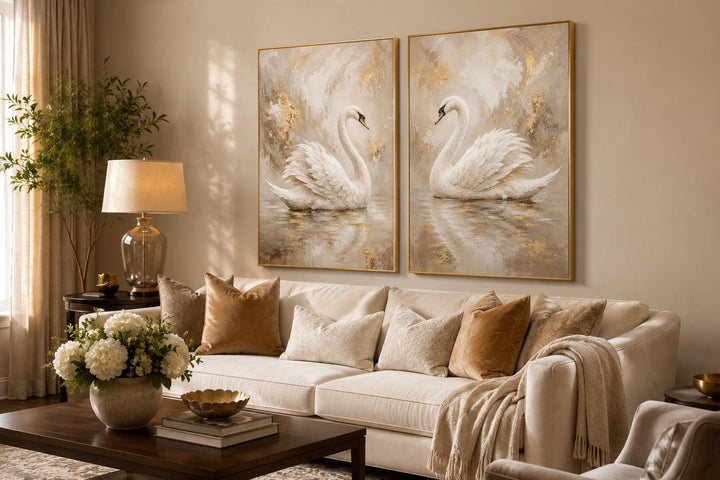 Set of 2 white swan canvas art prints with gold accents hanging above a cream sofa in a glam room.