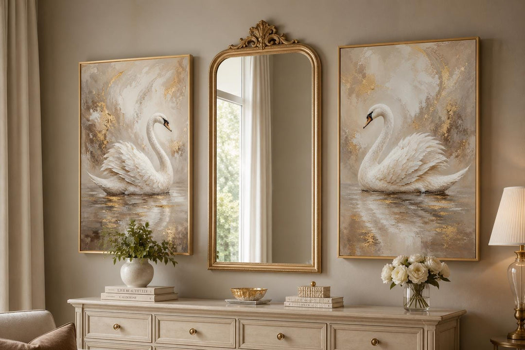 Set of 2 white swan canvas art prints with gold accents on a wall flanking a gold arched mirror.
