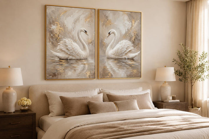 Set of 2 white swan canvas art prints with gold accents hanging above a bed in a glam bedroom.
