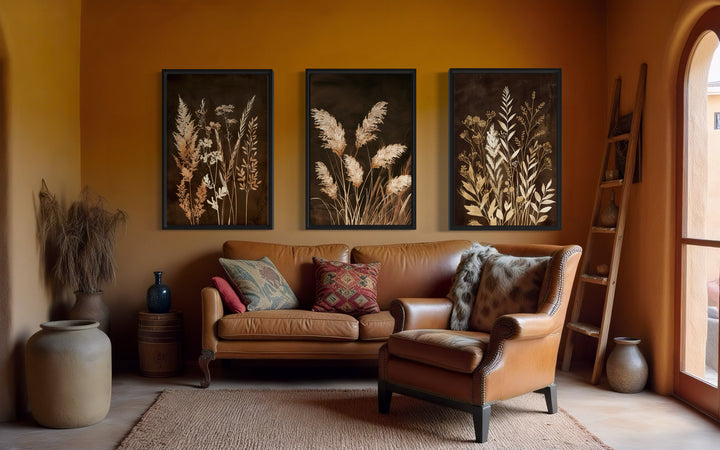 Set of 3 brown and beige boho grass canvas wall art prints hanging above a leather sofa.